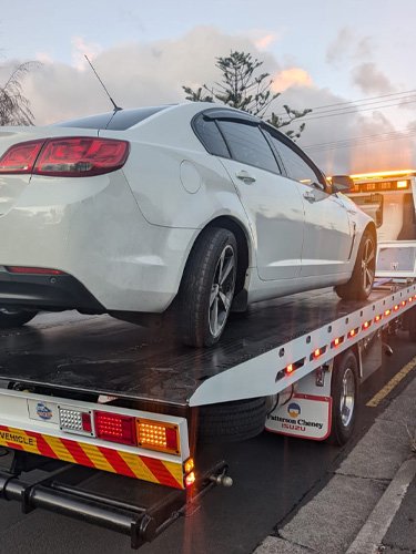 Big Boy's Tow truck towing a white sedan from a street